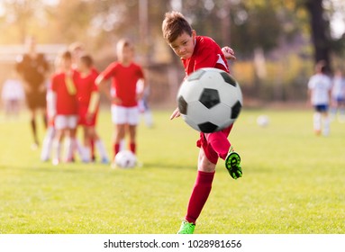 Boy kicking football on the sports field during soccer match