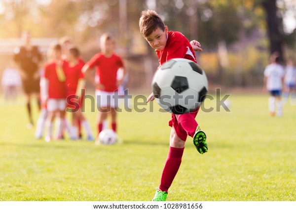 Boy kicking football on the sports field during\
soccer match