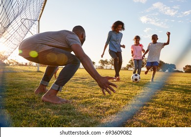 A boy kicks a football during a game with his family - Shutterstock ID 693609082