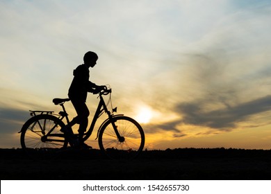 Boy , Kid 10 Years Old Riding Bike In Countryside, Silhouette Of Riding Person At Sunset In Nature