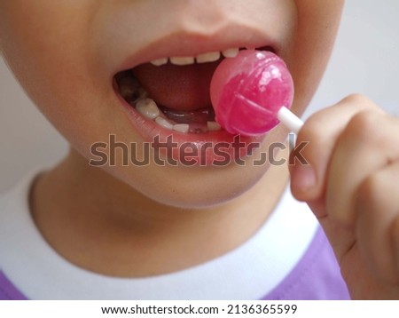 Boy kid consuming sweet candy lollipop with sugar added, causing loss teeth and unhealthy oral care. closeup photo, blurred.