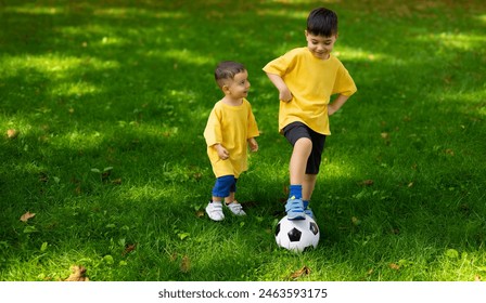 boy kid playing football in park on grass.child with ball in hands lying on ground.siblings, brothers and father,dad and son,playing together. balloon under man arm.getting ready for championship - Powered by Shutterstock