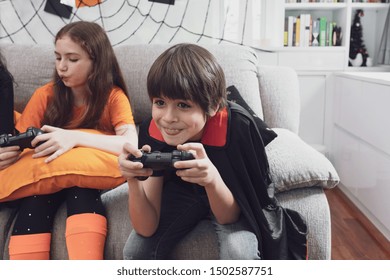 Boy Kids Smiling And Dress Up As Halloween Vampire Costume Holding Joystick To Play Halloween Game In Living Room At Home