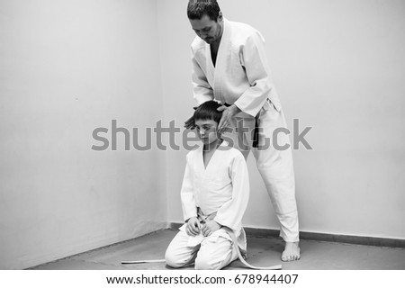 A boy in a kimono has an aikido training with a coach