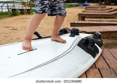 Boy learn to stand on the surf on the beach on the shore of the lake, sea, water sports, active lifestyle, vacation, heat, rest.