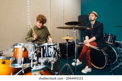 Boy learning how to play drums. Music lesson with teacher.
