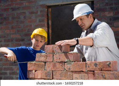 Boy learning to lay bricks on construction site