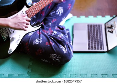 Boy Learning Online Electric Guitar Course Through His Laptop At Home During Covid-19 Pandemic Lockdown. Remote Music Class Online Learning And Distance Education Through Mobile And Wireless Concept. 