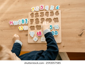 boy learns to count by laying out numbers from 1 to 20 on the board, boy 4-5 years old European appearance, at home in the living room sitting at the table, preparation for school