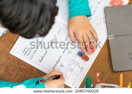 The boy learns to write uppercase Russian letters. Text translation: 