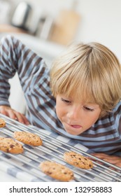 Boy Licking His Lip  In Front Of Cookies In The Kitchen