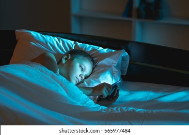 The boy lie on the bed and phone - Shutterstock ID 565977484
