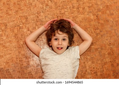 Boy Lies On Warm Clean Floor At Home. Cork Floor