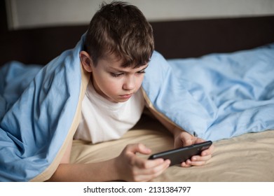 The Boy Lies Under The Covers Playing The Phone