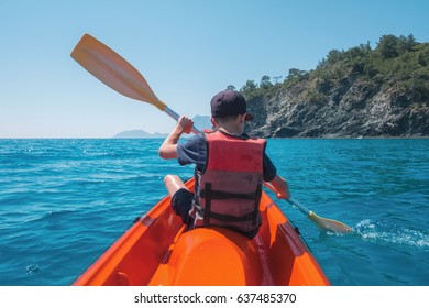 Boy in life jacket on orange kayak. Sunny day on mediterranean sea. Summer time - Shutterstock ID 637485370