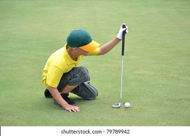 Boy Lining Up A Putt On The Green