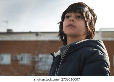 Boy looking away thoughtfully while standing outdoors in city