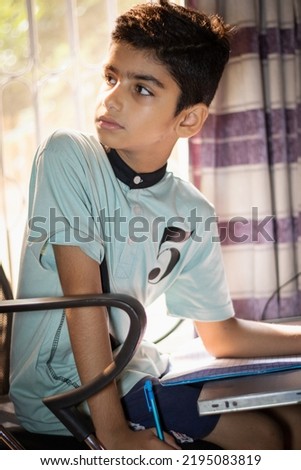 A boy is looking back while holding a notebook and pensil