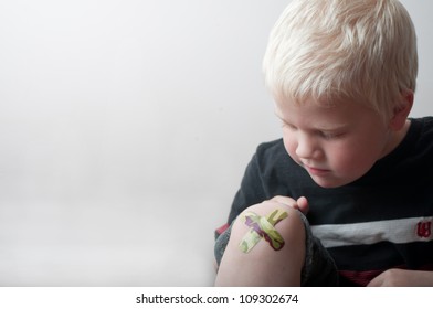 Boy Looking At Band Aid On Knee