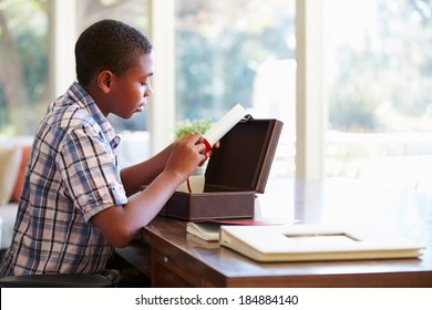 Boy Looking At Document In Keepsake Box On Desk