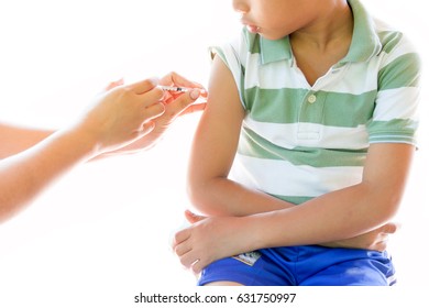 boy looking at his arm, while receiving vaccine