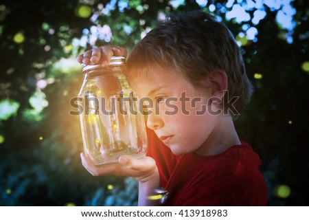 Boy looking into a jar of fireflies