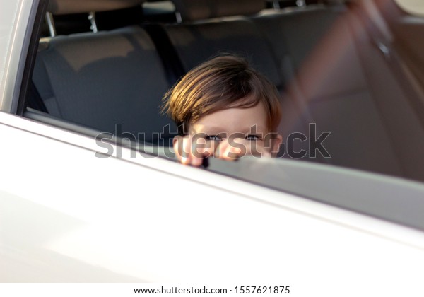 Boy looking out of car window, close-up.Portrait of\
happy smiling little kid sitting in car and looking away.Little boy\
looking out of the car window.Shot of adorable boy traveling in\
backseat of car