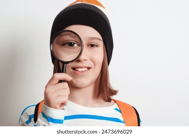 Boy looking through magnifying glass. Schoolboy holding the magnifying glass. Children's interest. Portrait of student boy with magnifier. School, learning and development concept. - Powered by Shutterstock