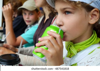 Boy Looks How Girl Drinks A Drink Of Red Aluminum Can