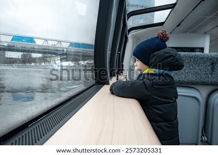 A boy looks out the window of a river tram.