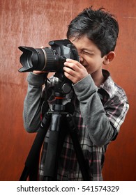 A boy looks through a camera fixed on a tripod