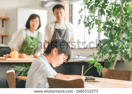 A boy in the lower grades of elementary school doing homework and studying in the dining room, living room, or living room of his home
