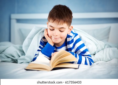 Boy Lying In Bed With A Book. Child Reading