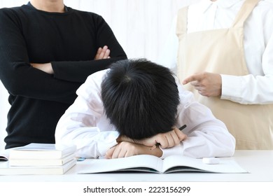 Boy lying face down on desk and scolding parents - Shutterstock ID 2223156299