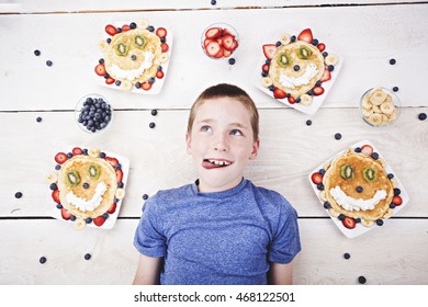 A boy lying next to some faced pancakes