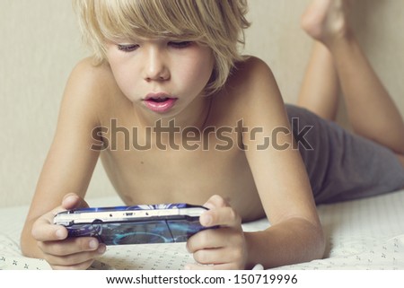 Boy lying on the bed and playing on the PSP