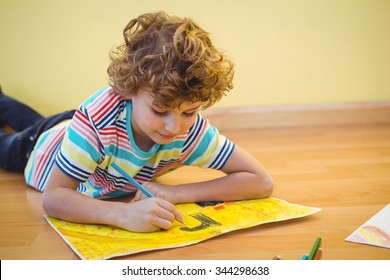 Boy lying on the ground colouring his picture - Shutterstock ID 344298638