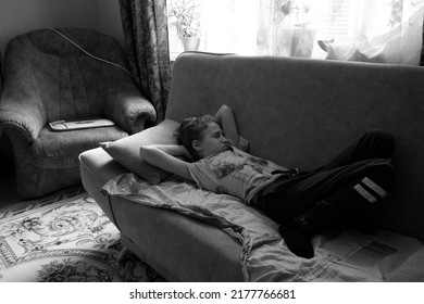 The Boy Is Lying On The Sofa With His Eyes Closed. The Black And White Photo Was Taken In Gomel, Belarus, On July 12, 2022