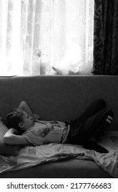 The Boy Is Lying On The Sofa With His Eyes Closed. The Black And White Photo Was Taken In Gomel, Belarus, On July 12, 2022