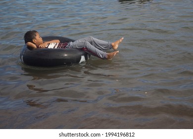 A Boy Lying On A Tire Floating In Water

Makassar, Indonesia - June, 20, 2021