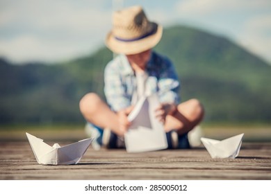 Boy Make A Paper Boat Sitting On The Wooden Pier