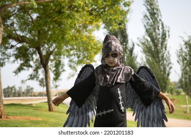 Boy In Make Up With White Face And Black Eyes, Dressed As Angel Of Death With Wings And Open Arms Celebrating Halloween. Autumn Concept, Trick Or Treat, Fear, Terror.