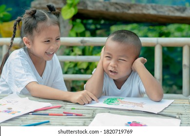 Boy Is Making Goofy Ridiculous Grimaces, Girl Is Pointing At Her With A Finger, Both Are Having Fun, Fooling Around,  Having A Pleasant Smile, Being In Good Mood