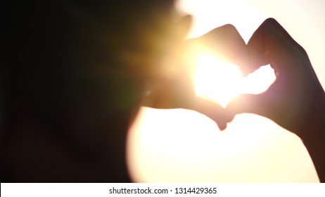 boy making heart with hands over sunset background. Silhouette hand in heart shape with sun inside. Vacation concept. Summer holidays. Tourism. - Shutterstock ID 1314429365
