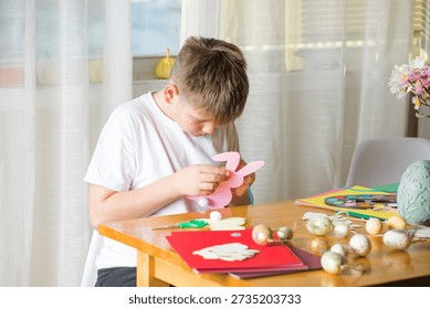 Boy making paper Easter bunnies, DIY craft activity for kids and family.