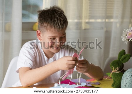 Boy making paper Easter bunnies, DIY craft activity for kids and family.