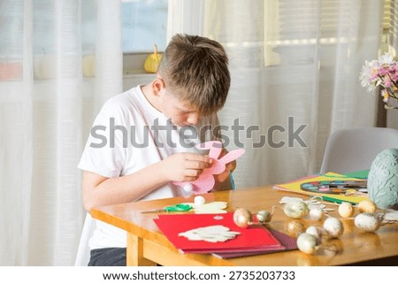 Boy making paper Easter bunnies, DIY craft activity for kids and family.