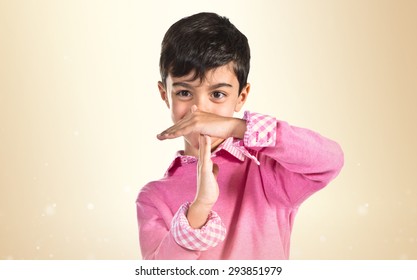 Boy Making Time Out Gesture Over Ocher Background