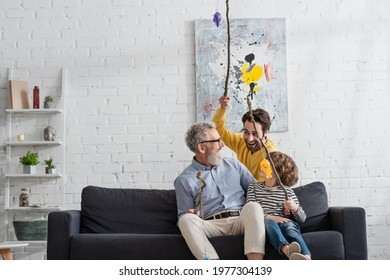 Boy And Man With Toy Fishing Rods Looking At Grandfather At Home