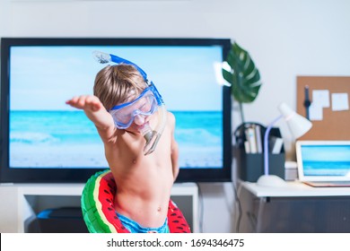 Boy in mask and snorkel dive imitating swimming near TV at home. Boy is having fun in mask and floating toy during the quarantine isolation. Stay at home. Play at Home. Coronavirus situation